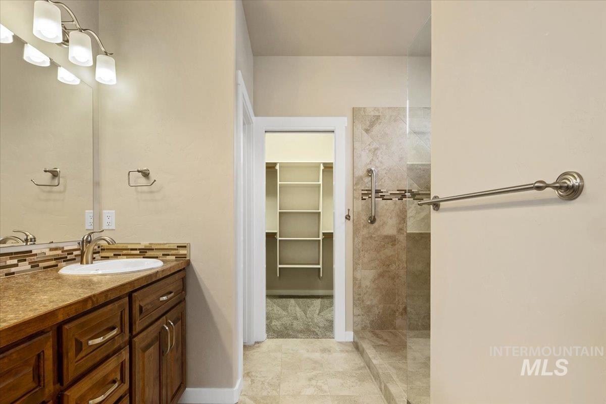 Full bathroom featuring vanity, a spacious closet, and walk in shower