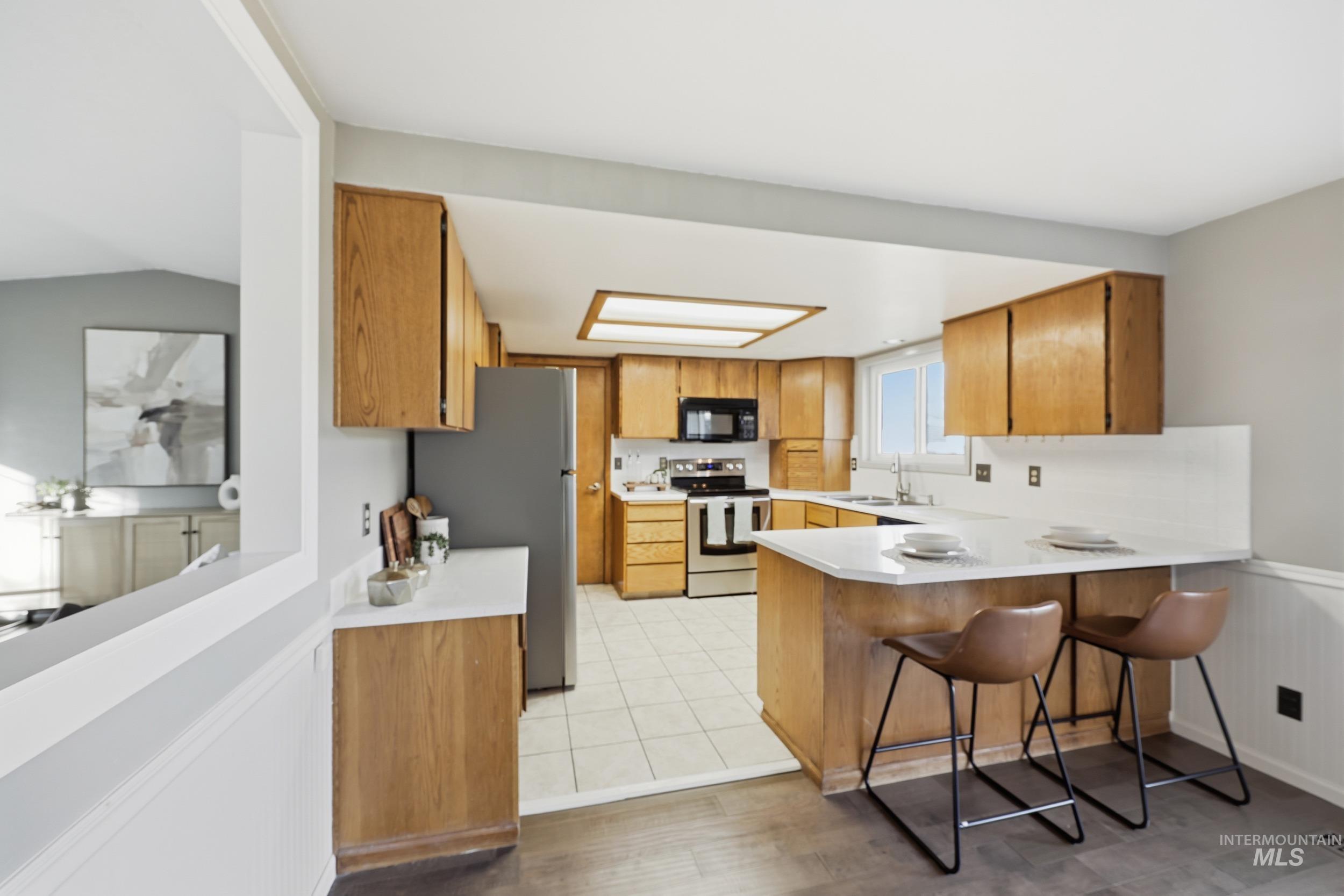Kitchen featuring a peninsula, light countertops, a breakfast bar area,  and stainless steel appliances.