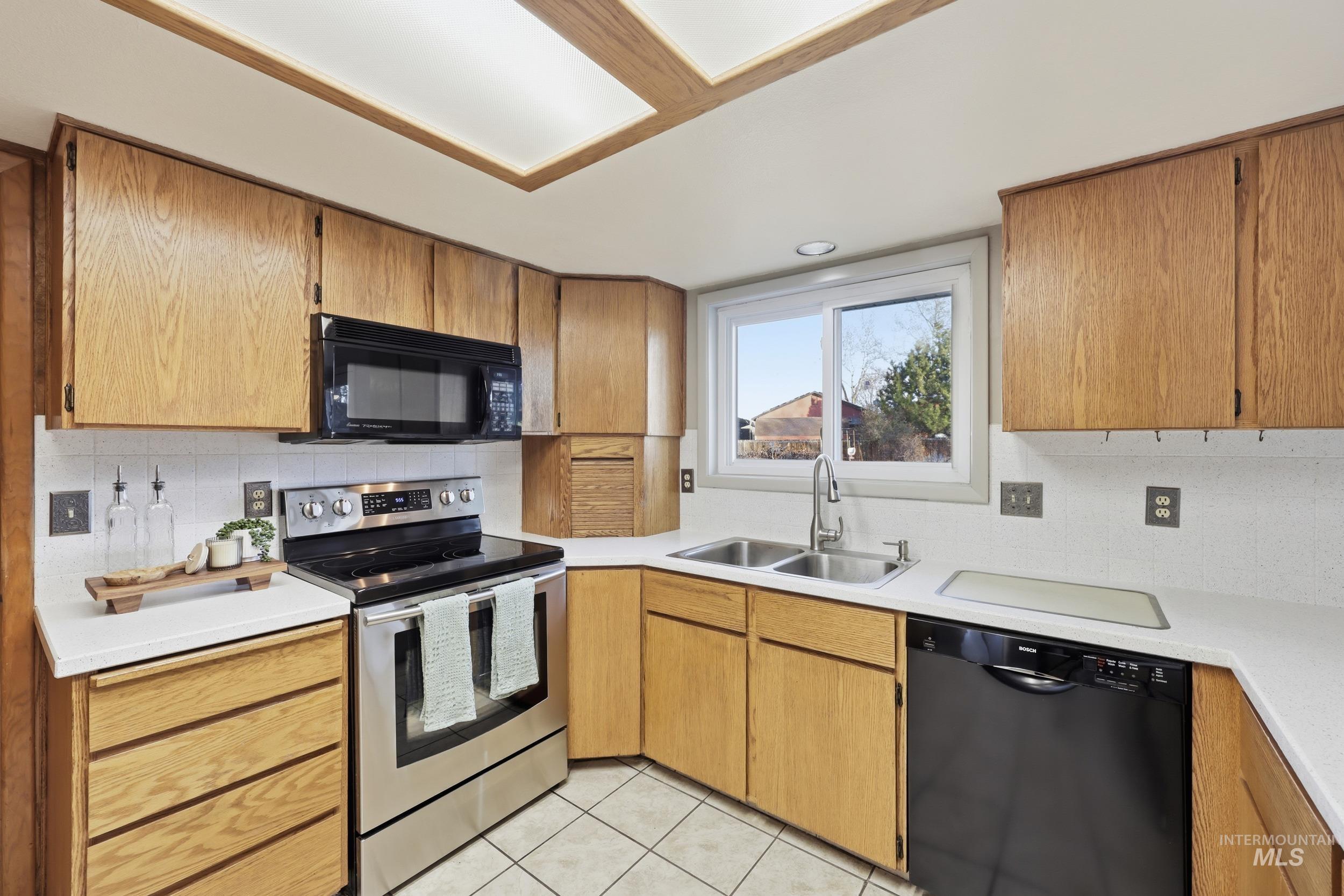 Kitchen with appliances, light countertops, light floors, and tasteful backsplash.