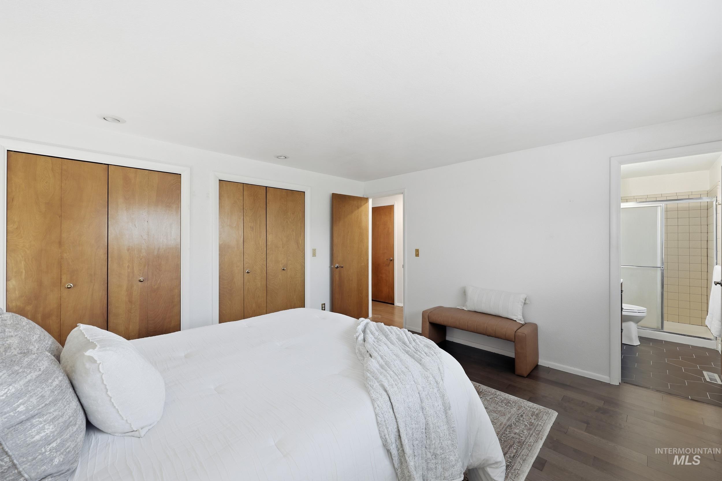 Bedroom featuring two closets, bright lighting, new engineered hardwood floors and ensuite bath.