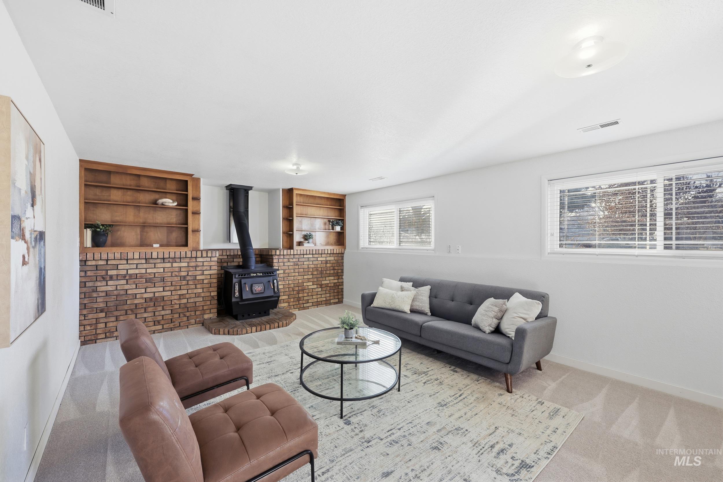 Newly carpeted living area featuring a wood stove and built in features with outlets.