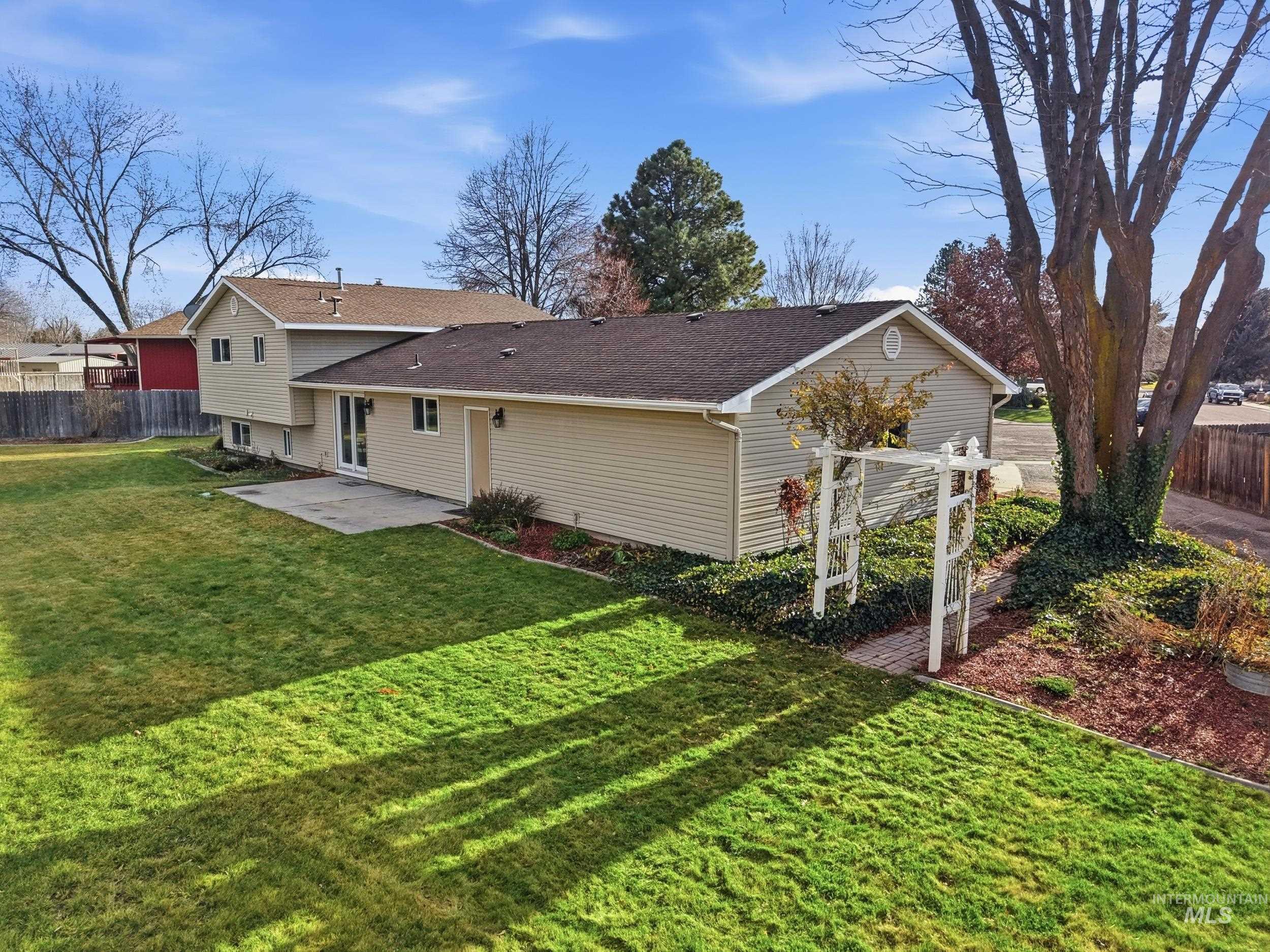 Rear view of house featuring a patio and a shingled roof.
