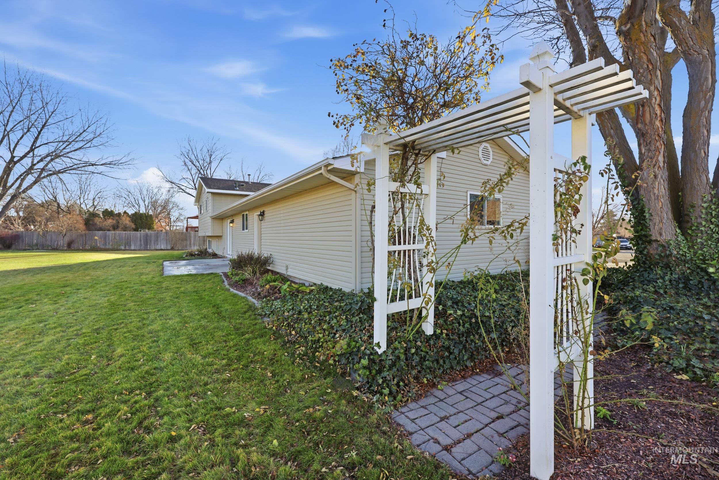 View of side of property featuring a patio, chimney, and arbor.