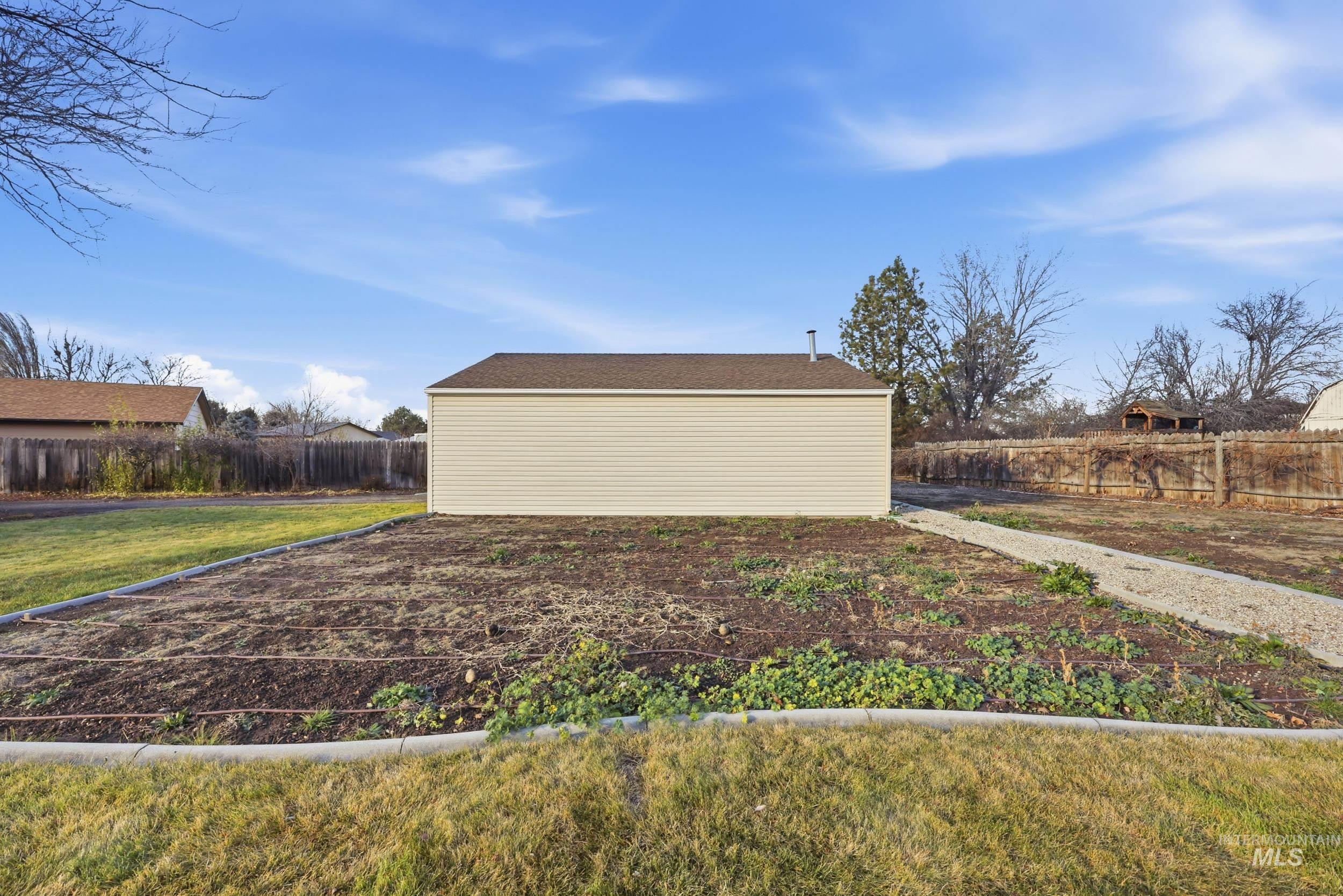 View of 30x30 shop exterior with a fenced backyard and drip irrigation.