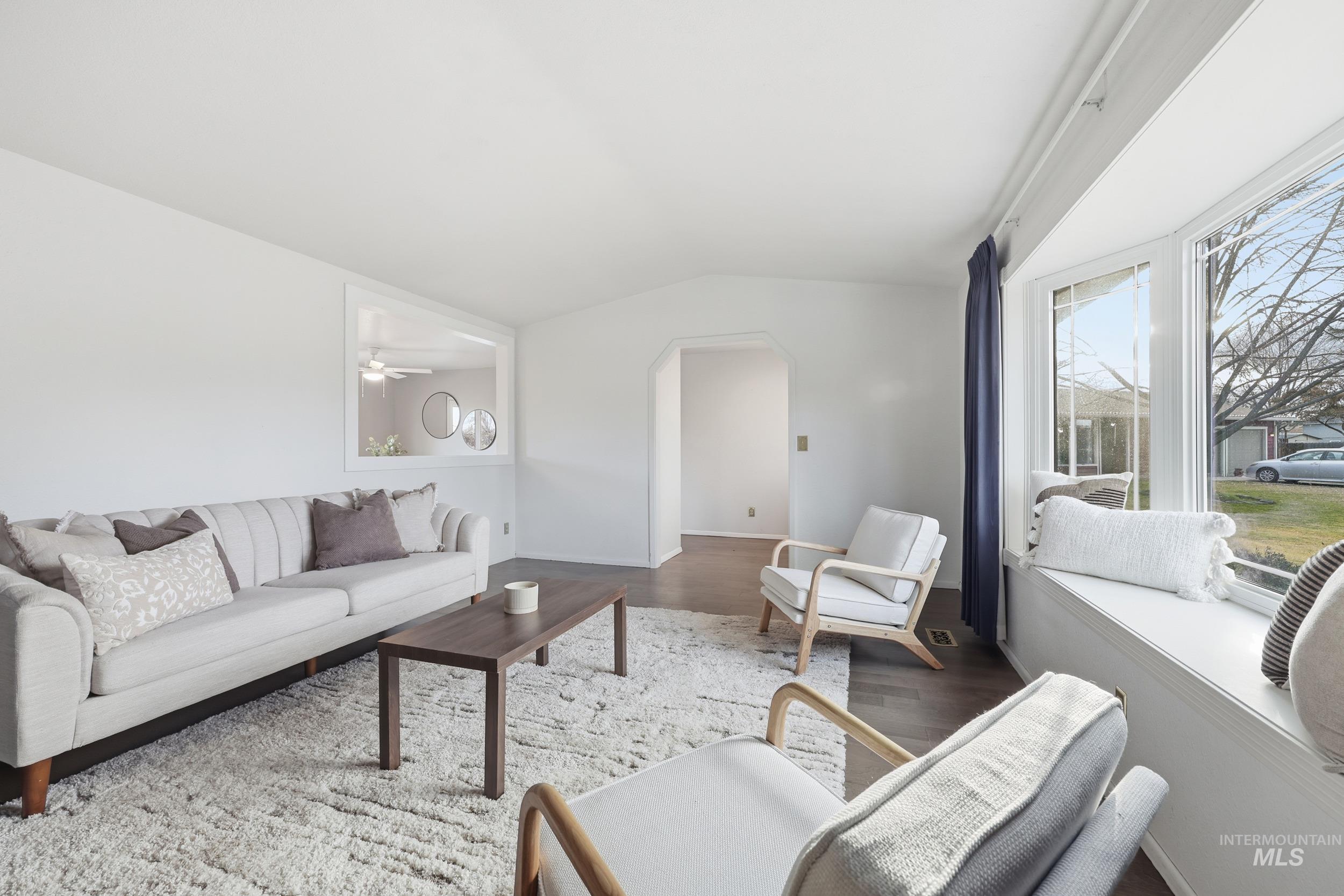 Living area with vaulted ceiling, new engineered hardwood floors, an arched walkway, and ceiling fan.