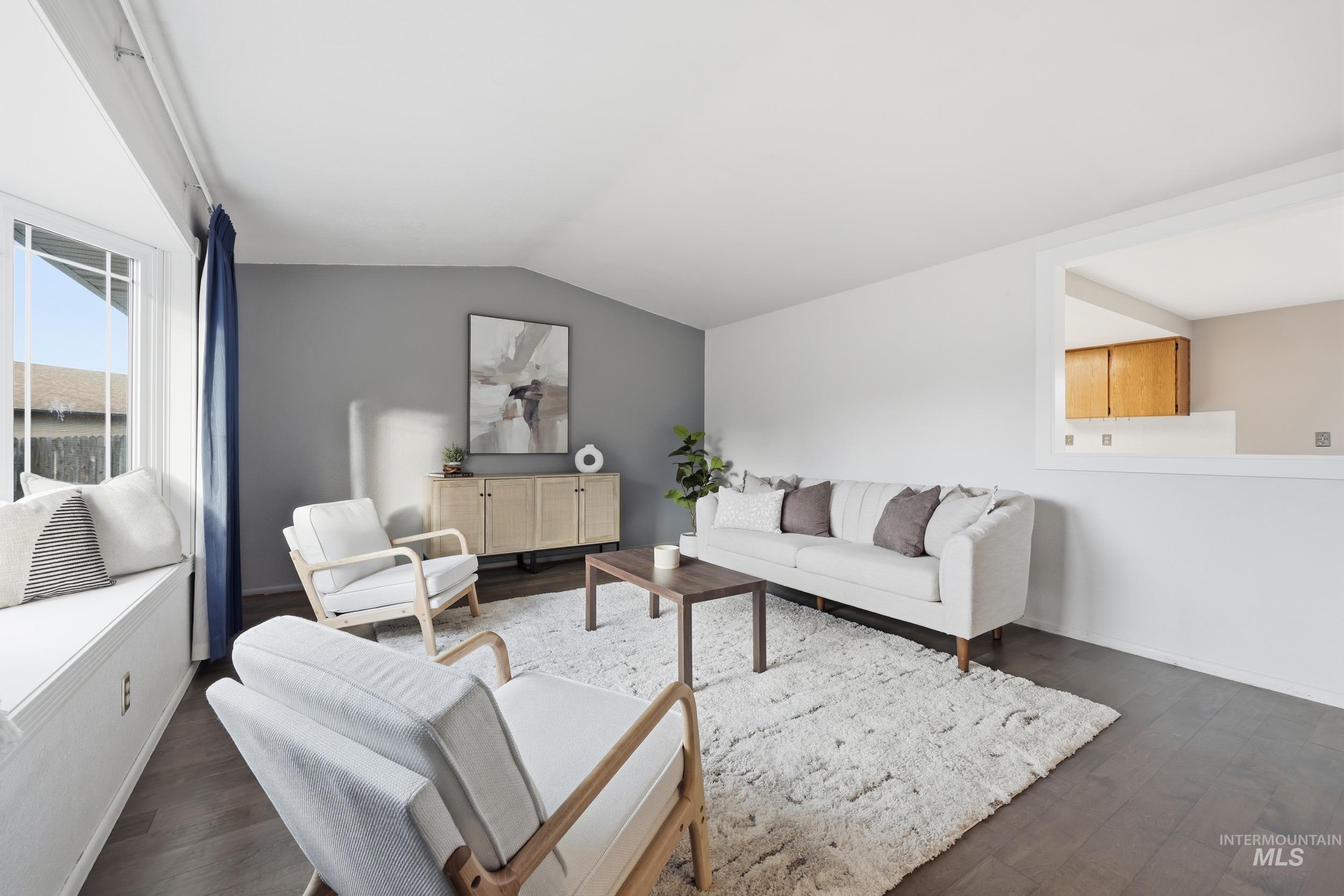 Living area with new engineered hardwood flooring, a lofted ceiling, and an open view into the dining and kitchen area.