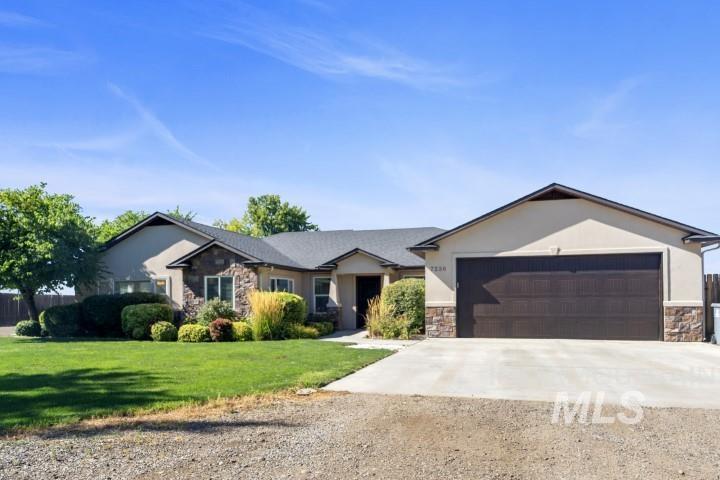 Ranch-style home with stone siding, driveway, a front lawn, stucco siding, and a garage
