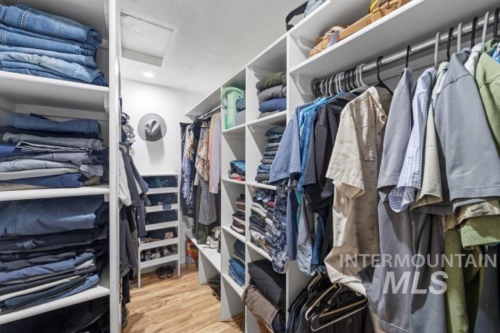 Walk in closet with attic access and light wood-style flooring