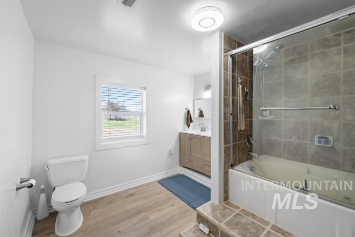 Full bathroom featuring vanity, bath / shower combo with glass door, and light wood-style flooring