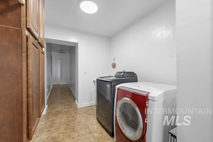 Laundry room with independent washer and dryer and light tile patterned floors
