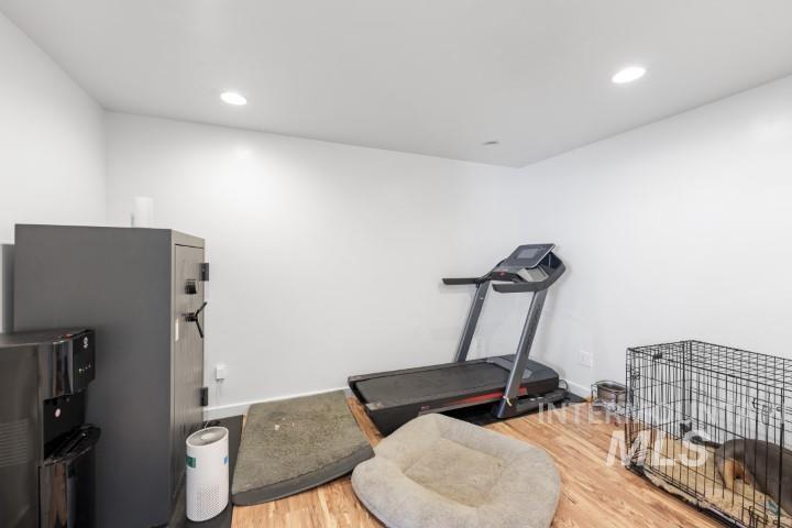 Exercise room with light wood finished floors and recessed lighting