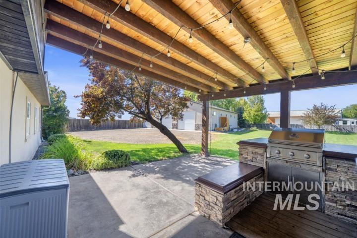 Fenced backyard with an outbuilding, a patio, and area for grilling