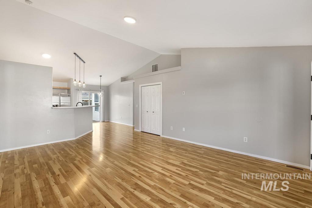 Unfurnished living room featuring light wood finished floors, vaulted ceiling, and recessed lighting