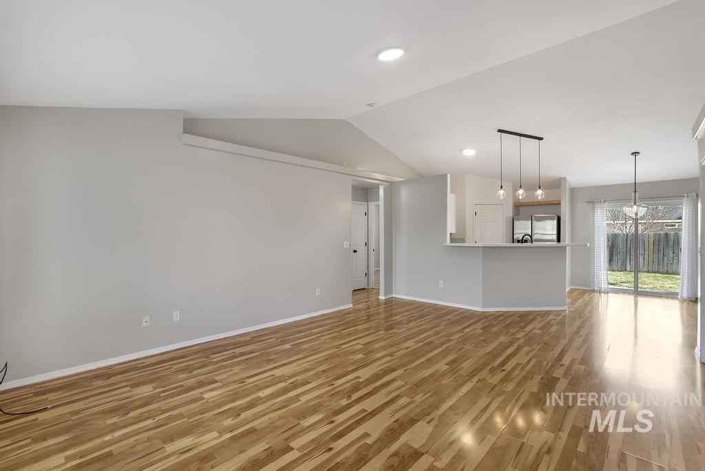 Unfurnished living room with vaulted ceiling, wood finished floors, recessed lighting, and a chandelier