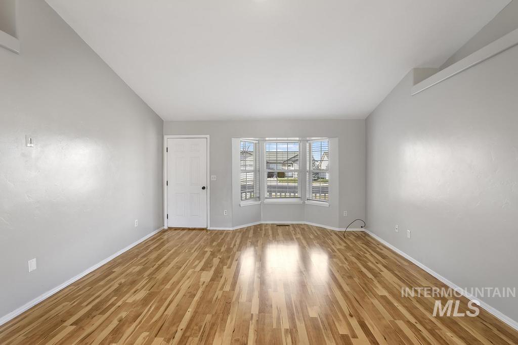 Empty room featuring lofted ceiling and wood finished floors