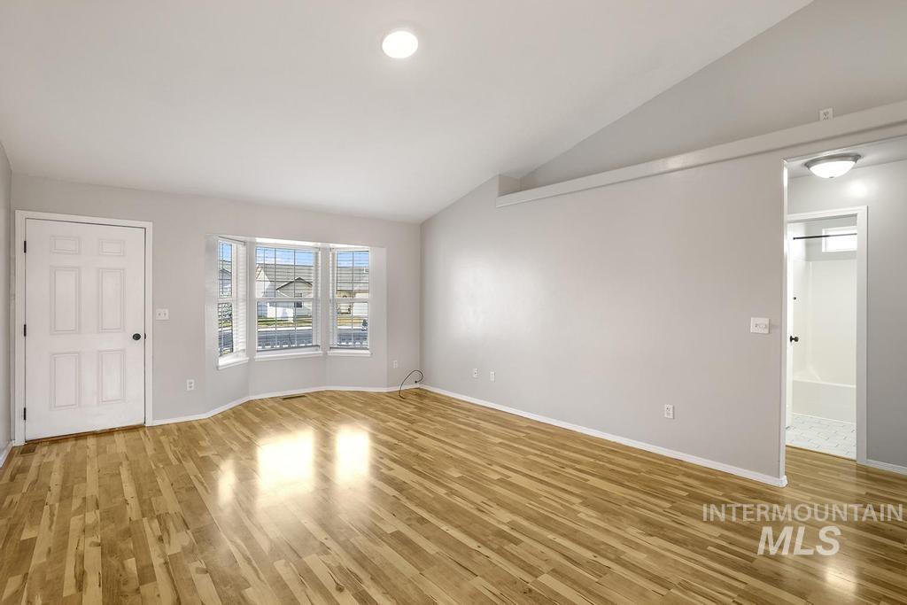 Spare room featuring vaulted ceiling, light wood-style flooring, and recessed lighting