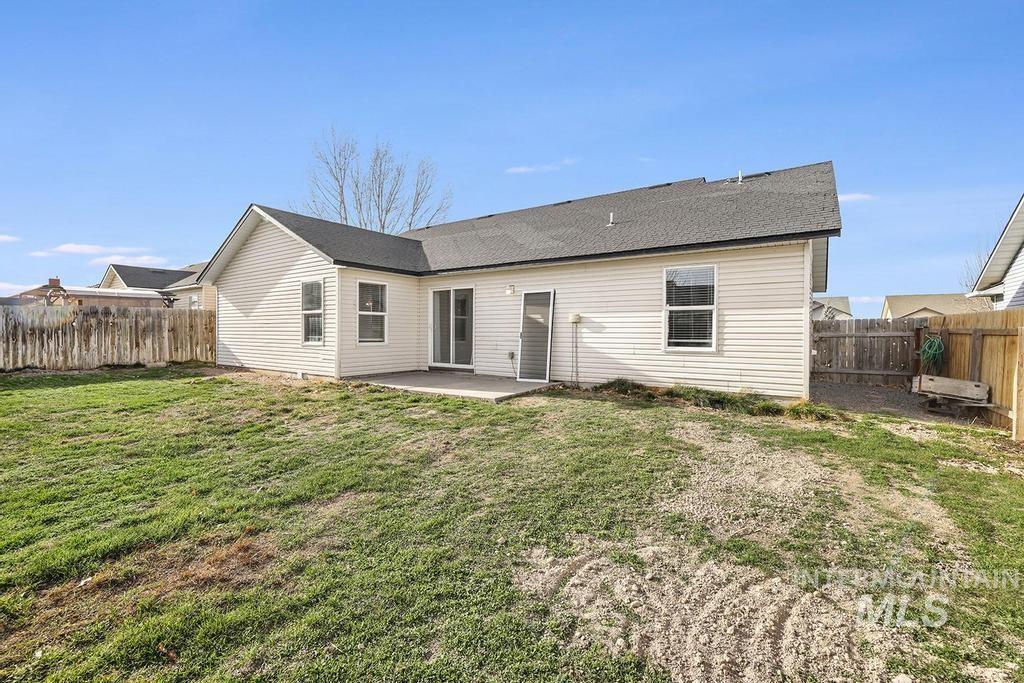 Back of property with a patio, a fenced backyard, and a shingled roof