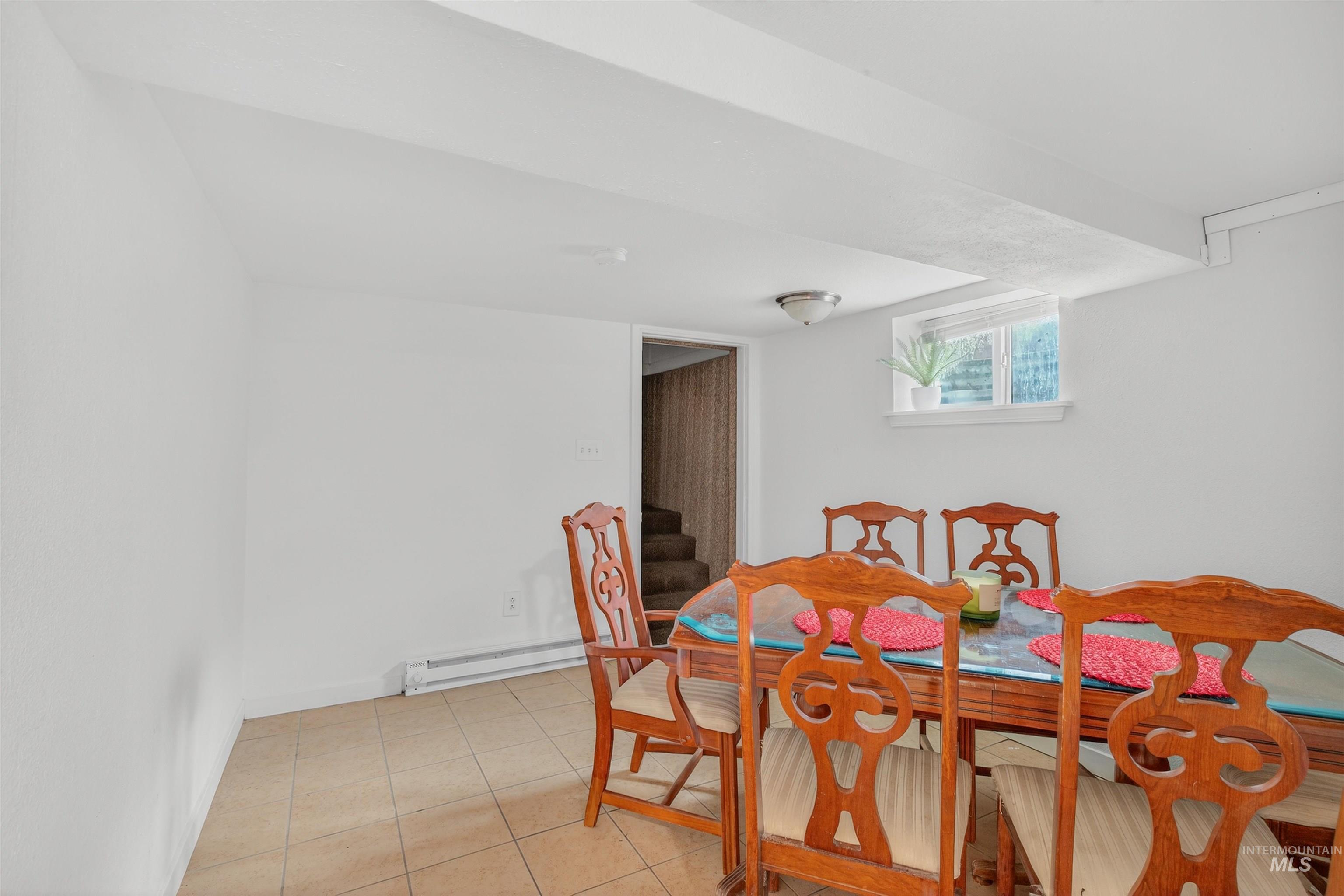 Dining space with light tile patterned floors and a baseboard heating unit