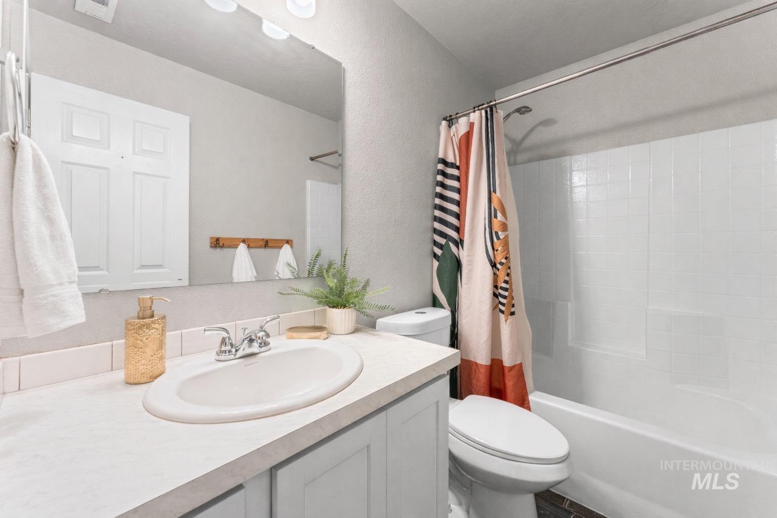 Bathroom featuring shower / bathtub combination with curtain, vanity, and a textured wall