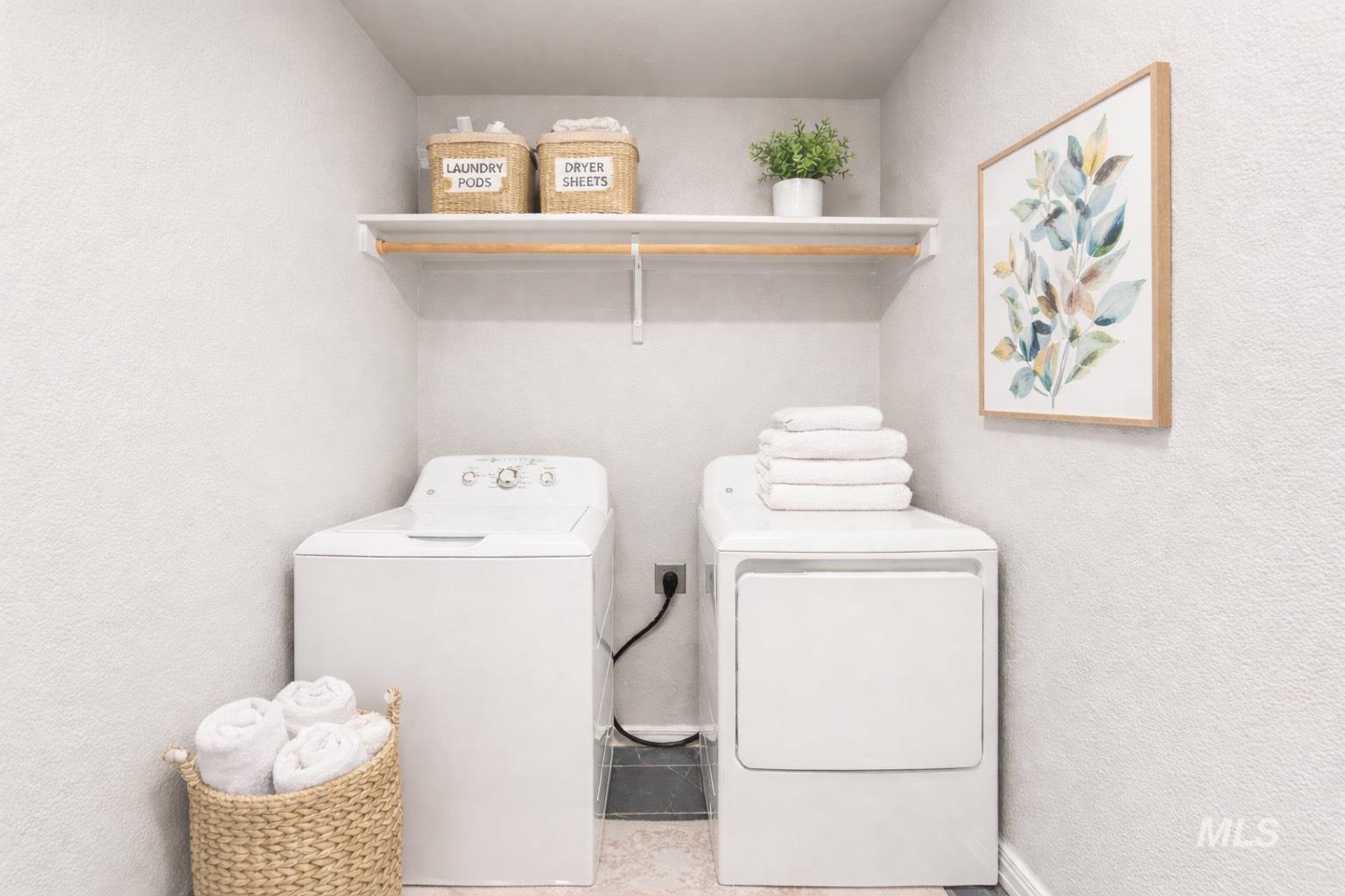 Laundry area with a textured wall and washer and dryer