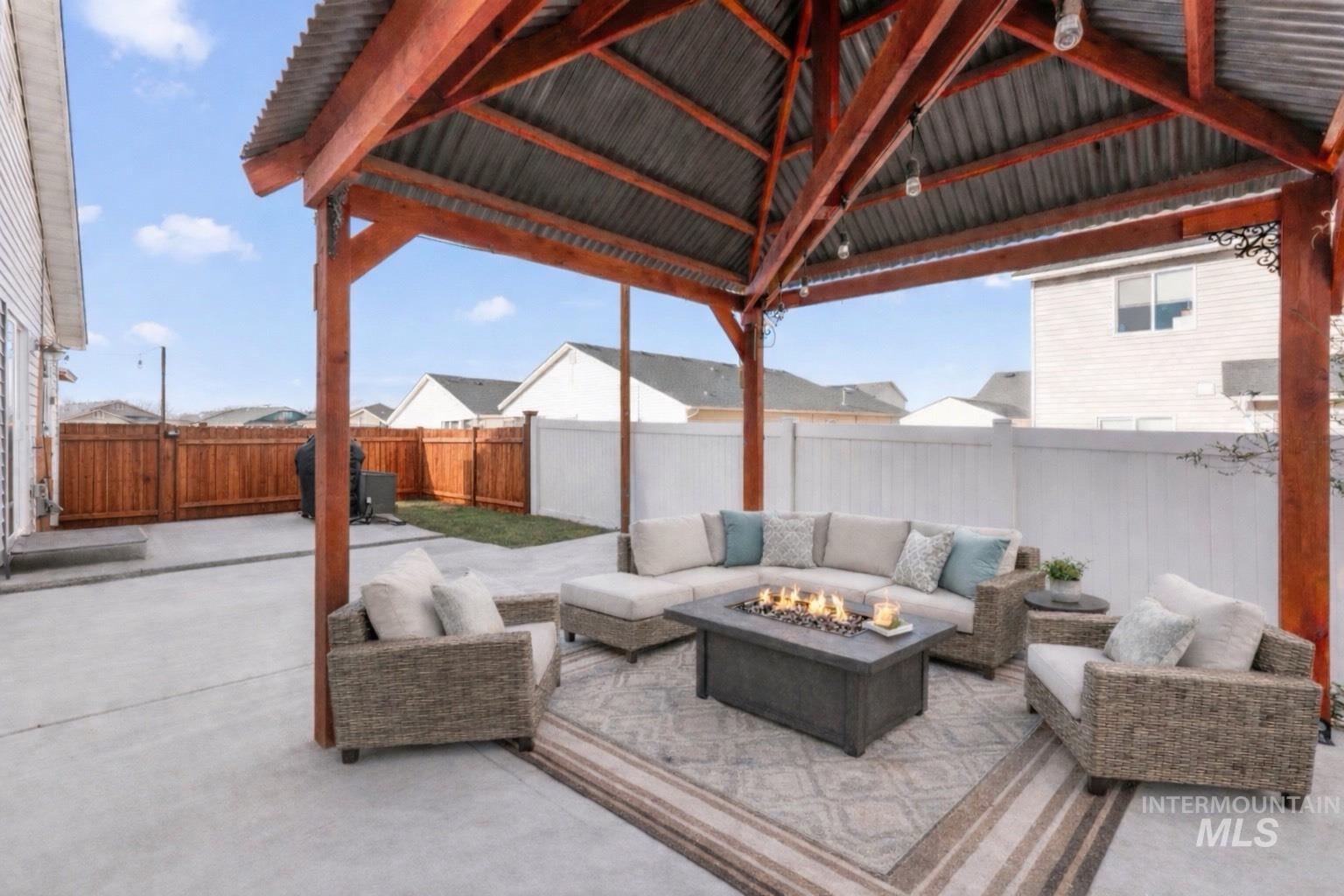 Fenced backyard featuring an outdoor living space with a fire pit and a patio