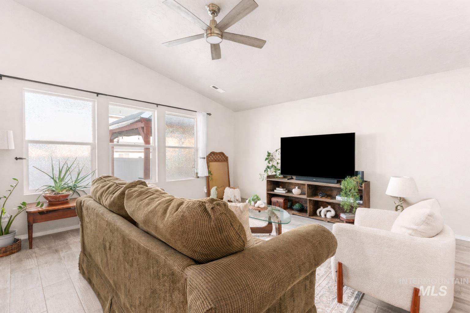 Living room featuring light wood-style flooring, ceiling fan, and lofted ceiling
