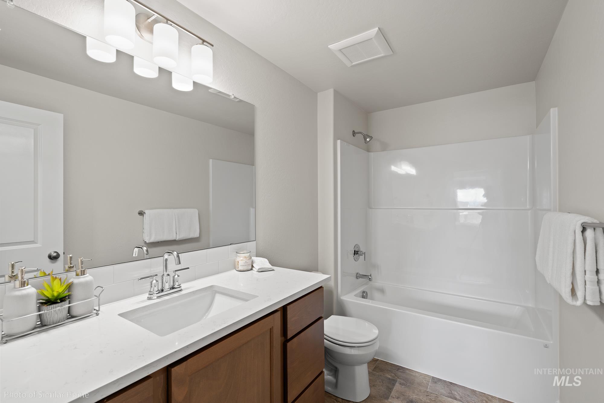 Full bathroom with vanity, shower / bath combination, stone finish floors, and backsplash