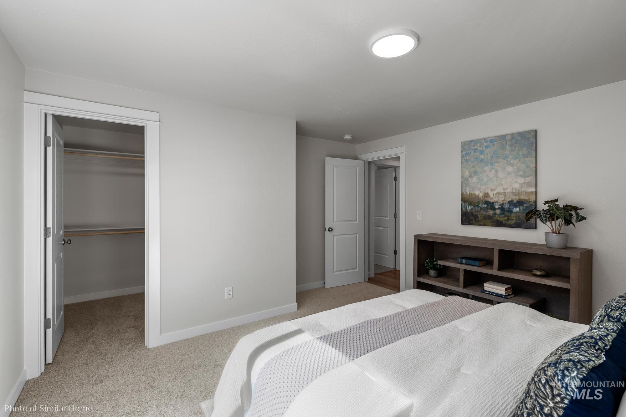 Bedroom with light colored carpet, a closet, and a spacious closet