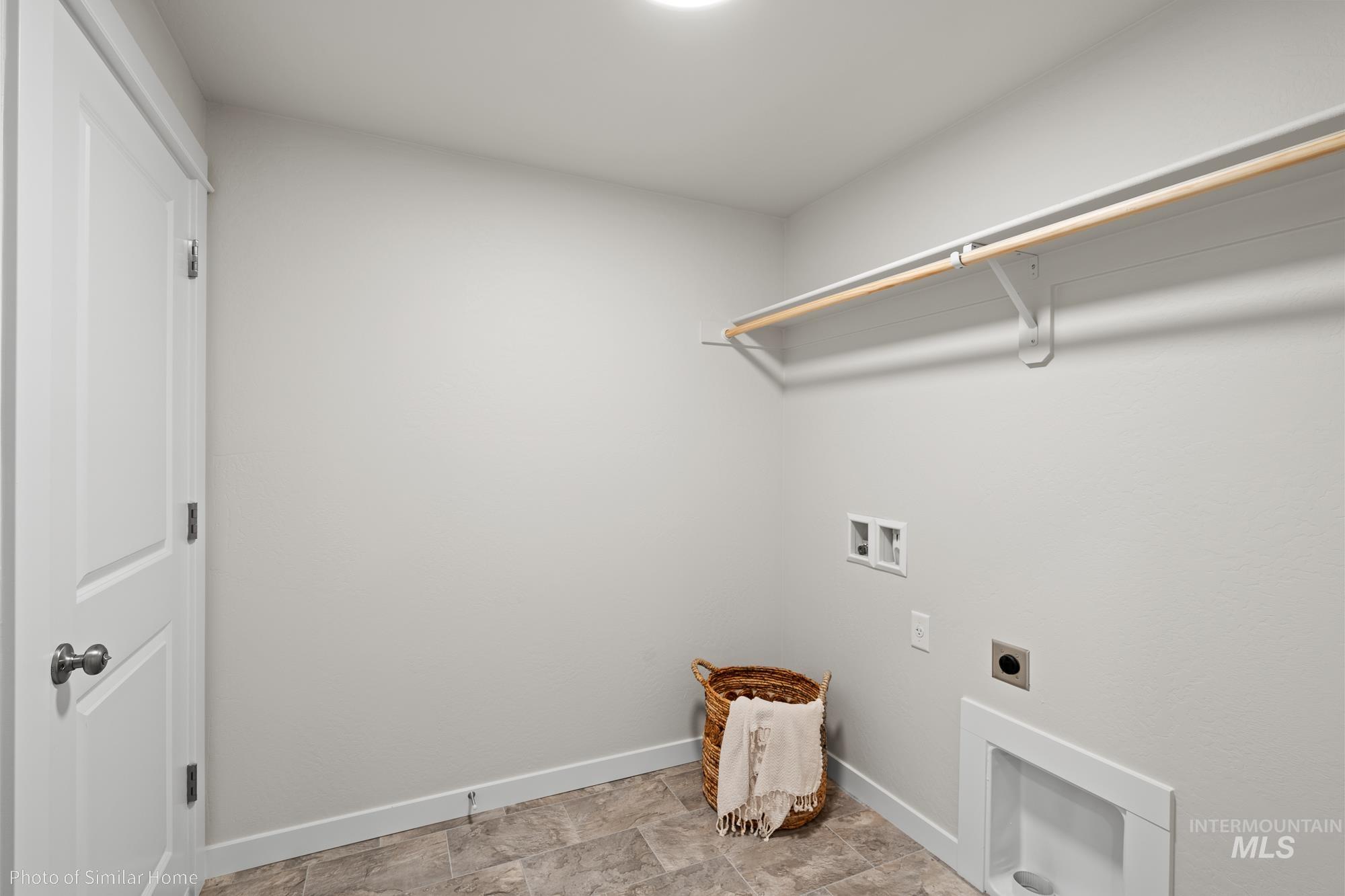 Washroom featuring electric dryer hookup, washer hookup, and stone finish flooring