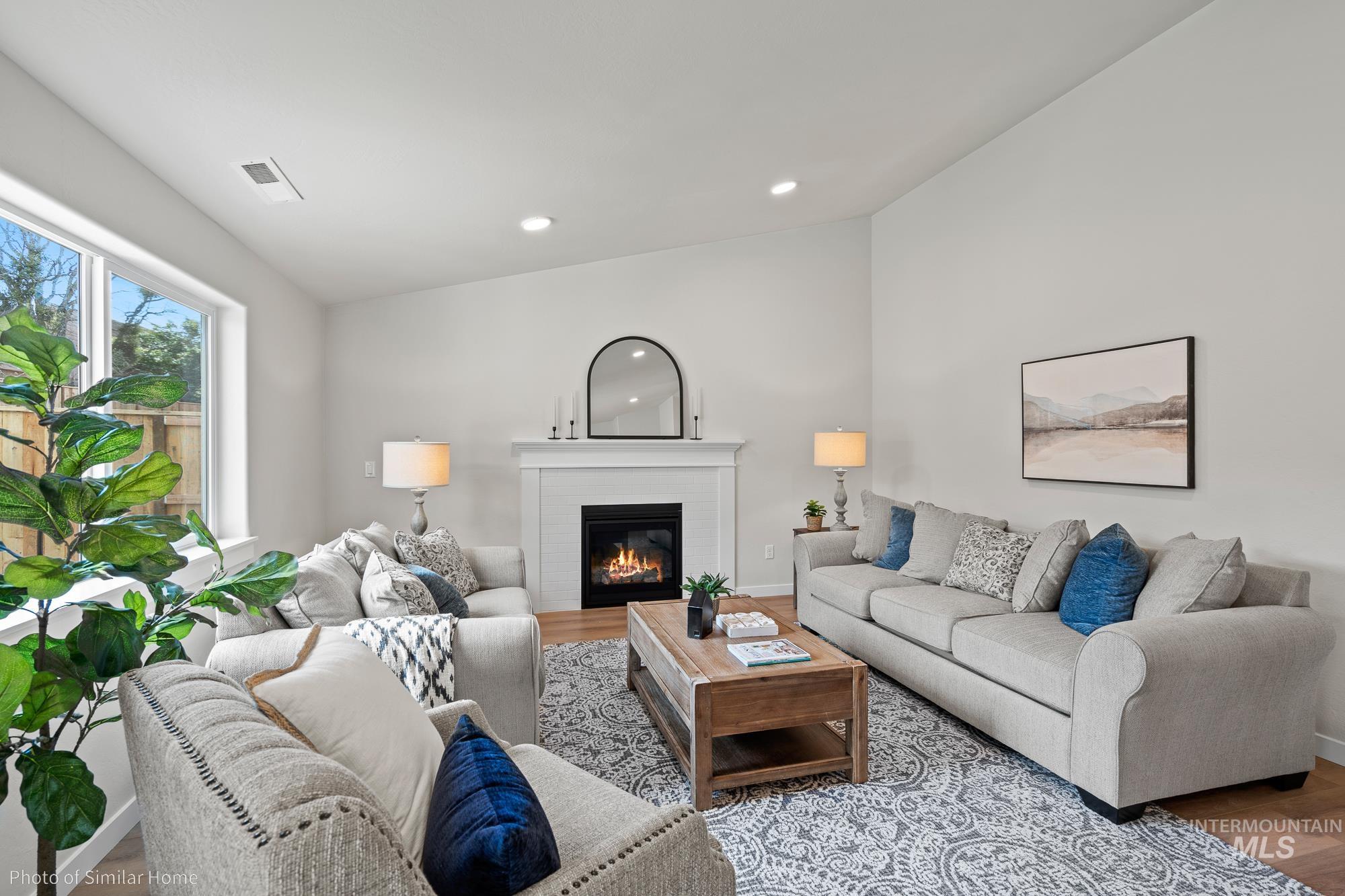 Living room featuring wood finished floors, a glass covered fireplace, and recessed lighting