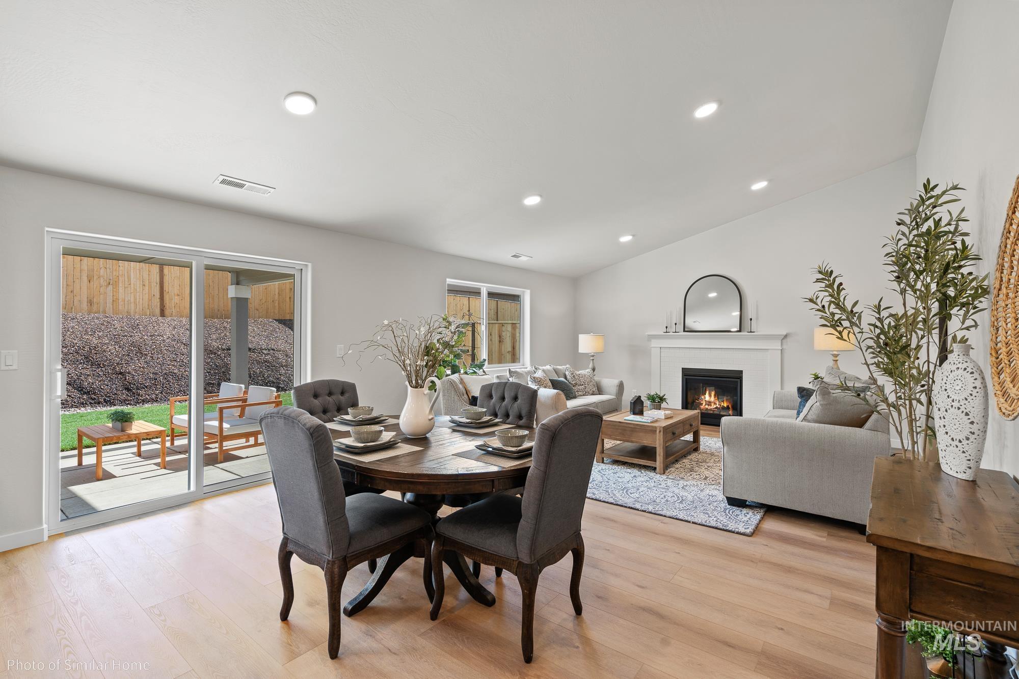 Dining space with light wood-style flooring, a glass covered fireplace, and recessed lighting