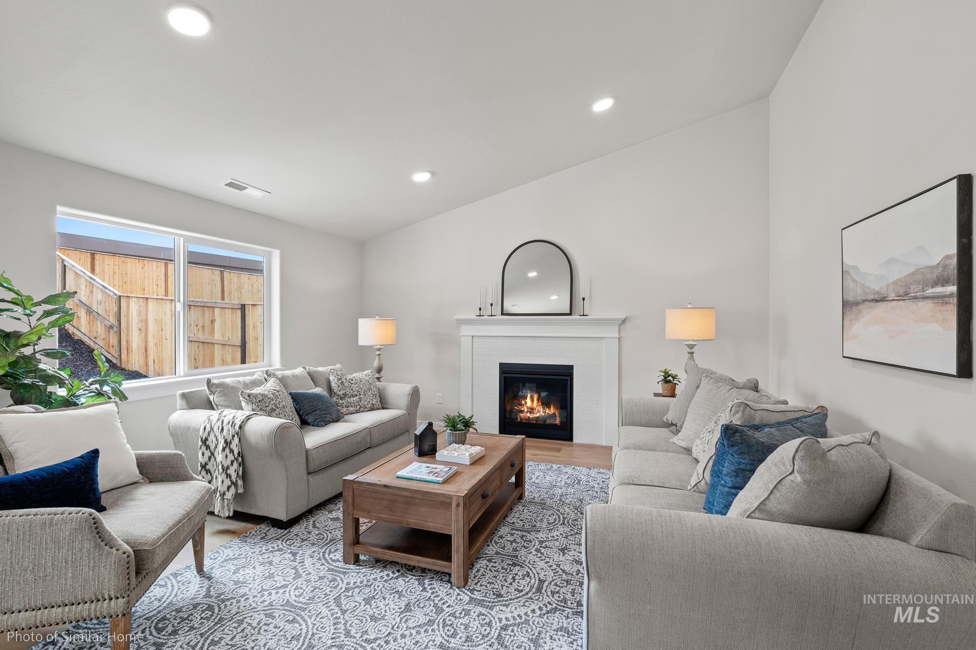 Living room with light wood-style floors, a glass covered fireplace, and recessed lighting