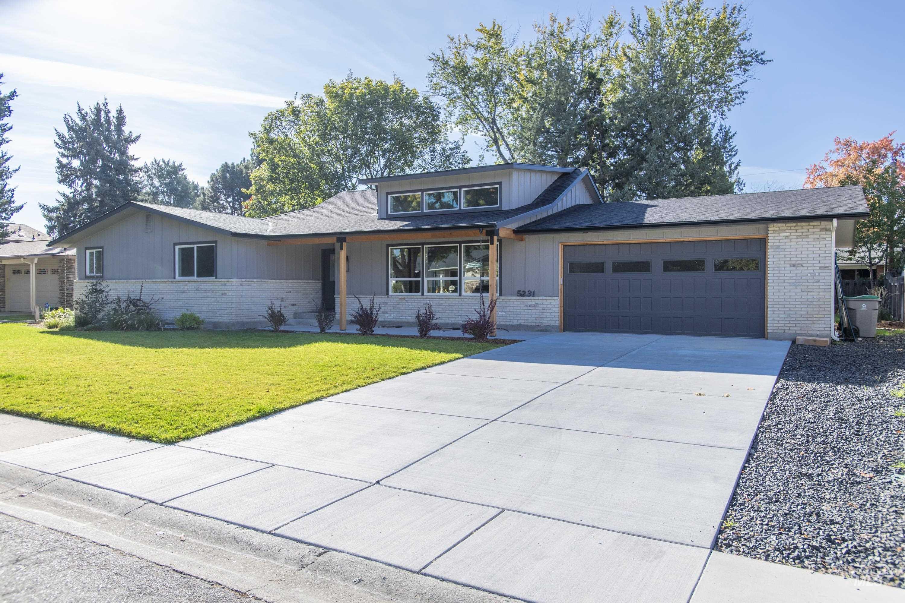 View of front of home with a front lawn, concrete driveway, an attached garage, and brick siding
