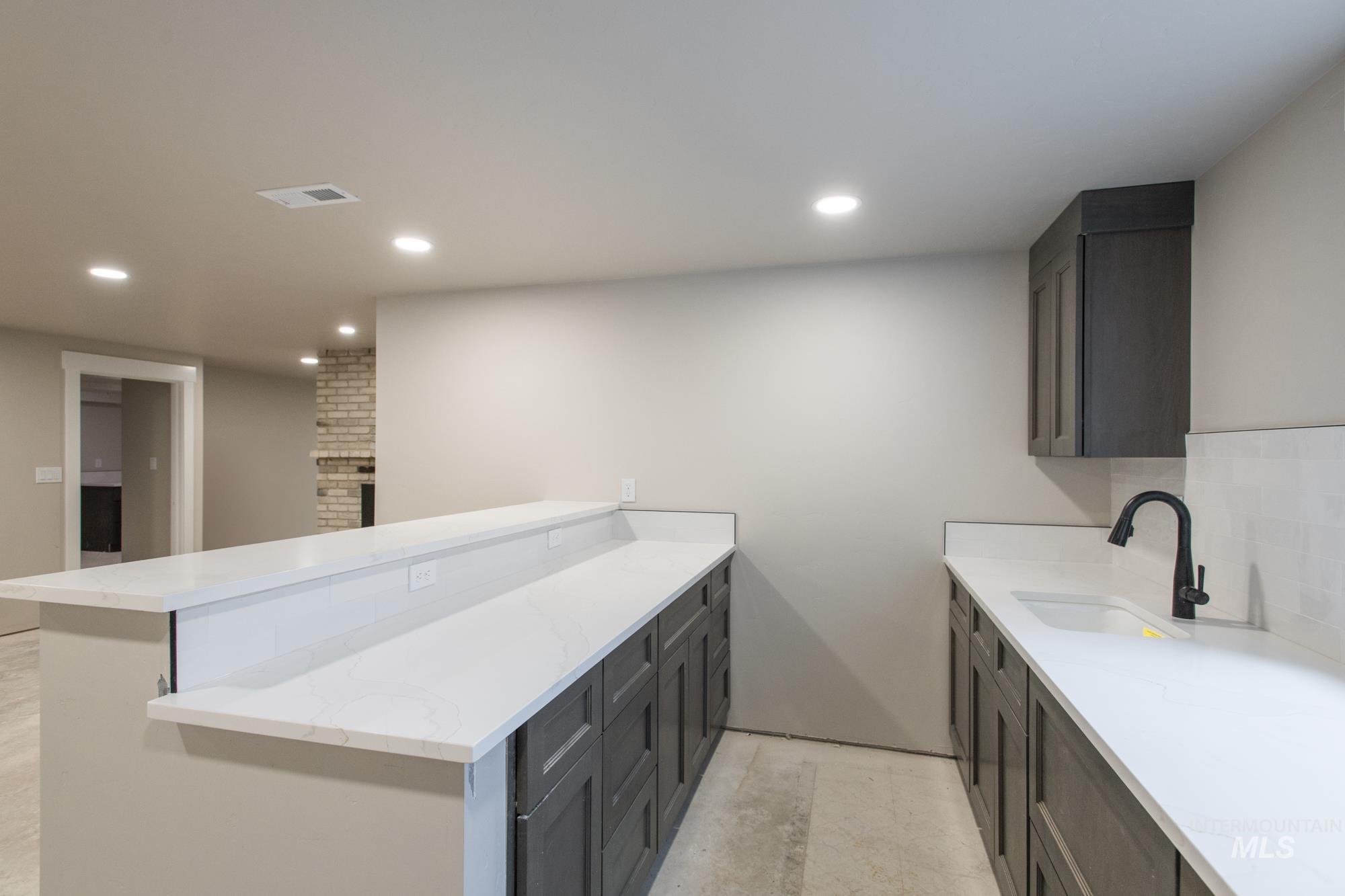 Bar area with light stone counters, recessed lighting, and decorative backsplash