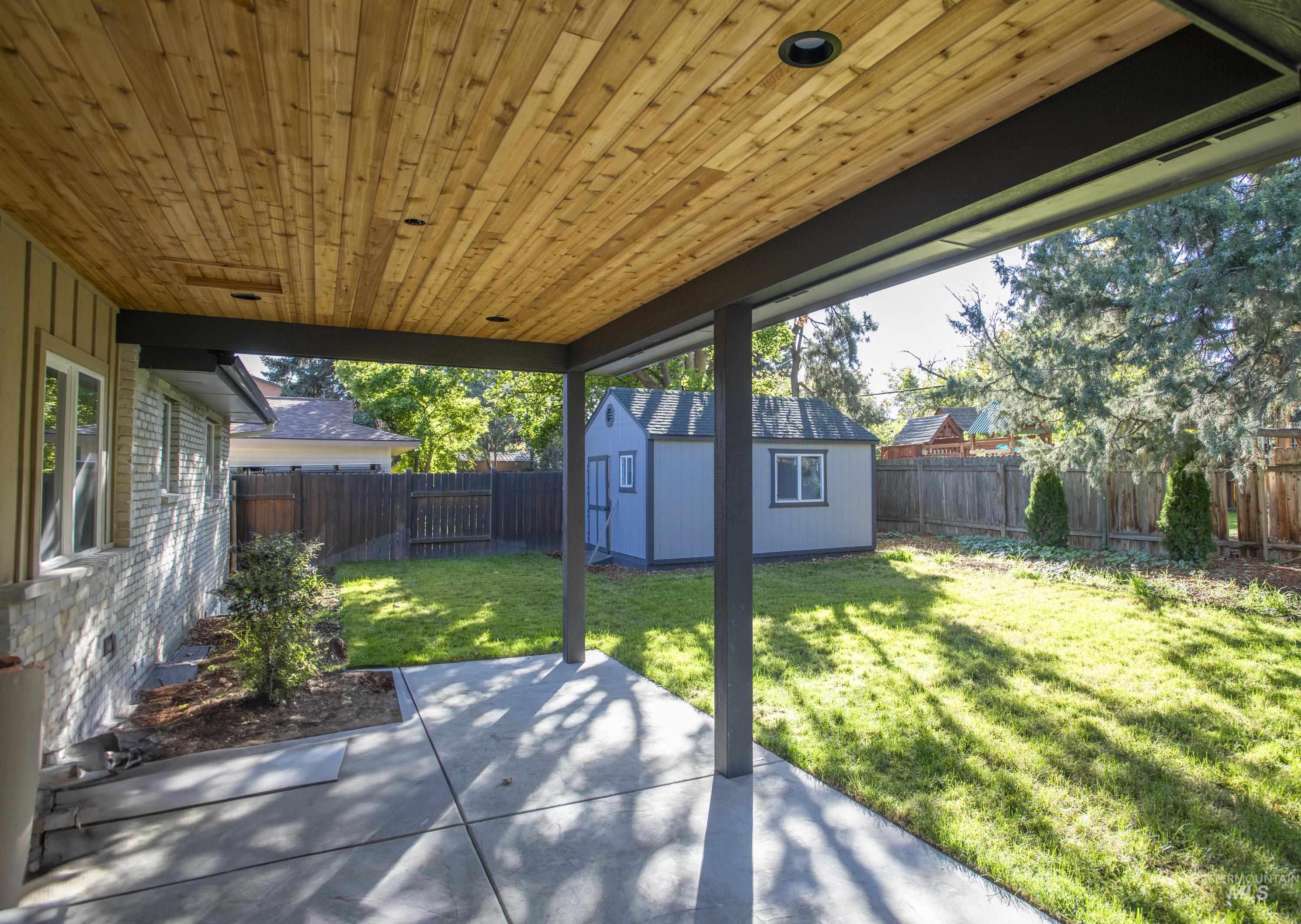 Fenced backyard with a ceder covered patio with ceiling fan to come and a powered shed