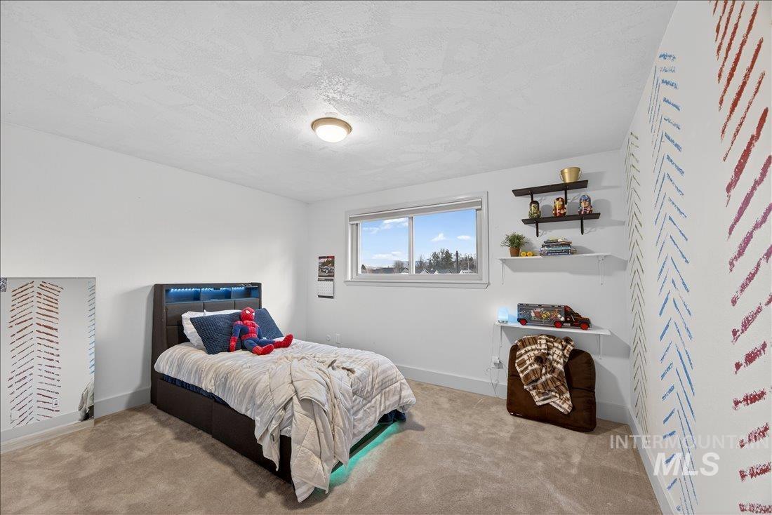 Bedroom with a textured ceiling and light colored carpet