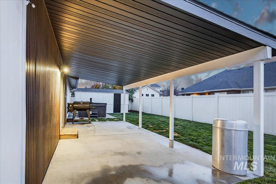 Fenced backyard featuring a patio, grilling area, and a storage unit