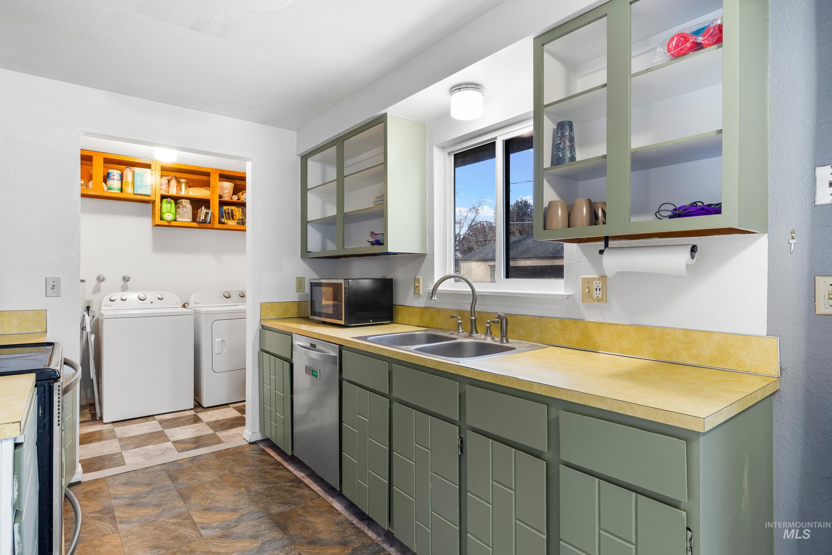Kitchen featuring green cabinetry, washer and dryer, open shelves, light countertops, and dishwasher