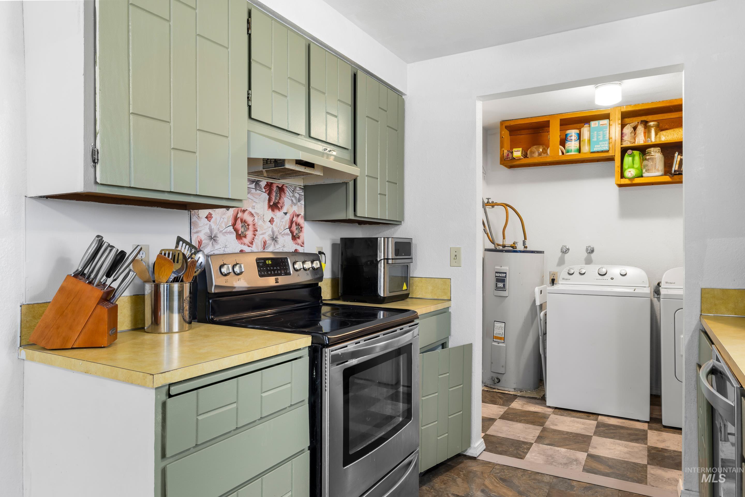 Kitchen with electric range, green cabinets, and light countertops