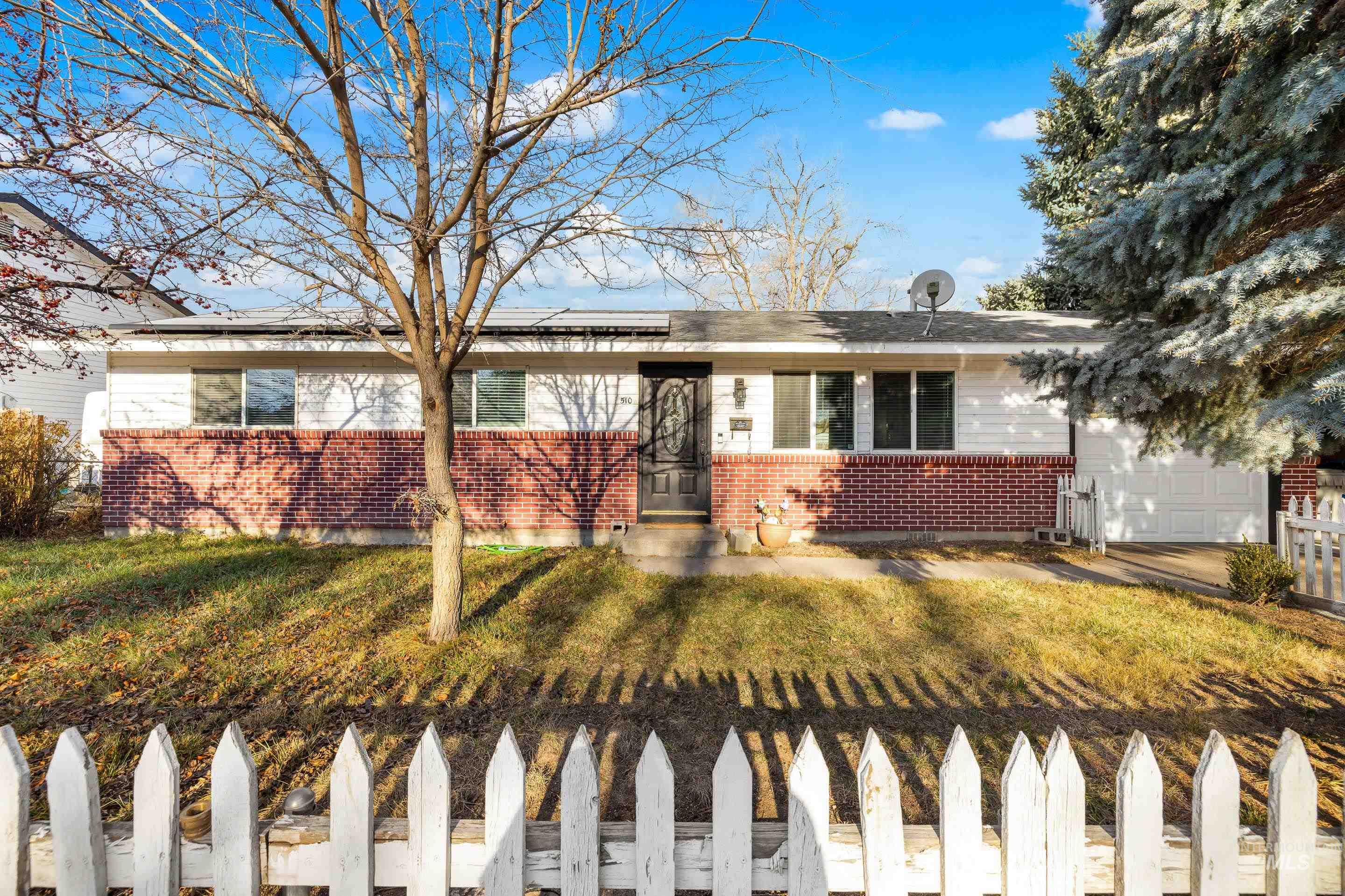 Ranch-style house with brick siding, solar panels, and a garage