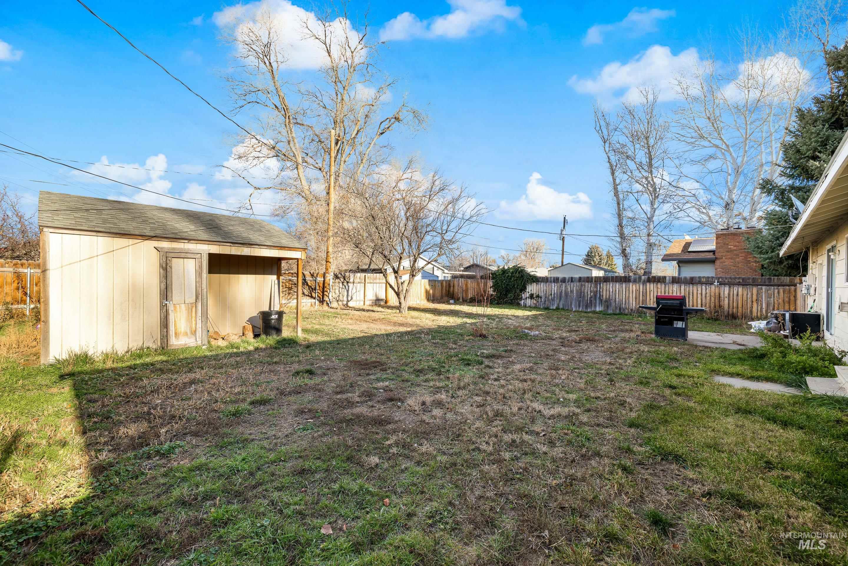Fenced backyard featuring an outbuilding