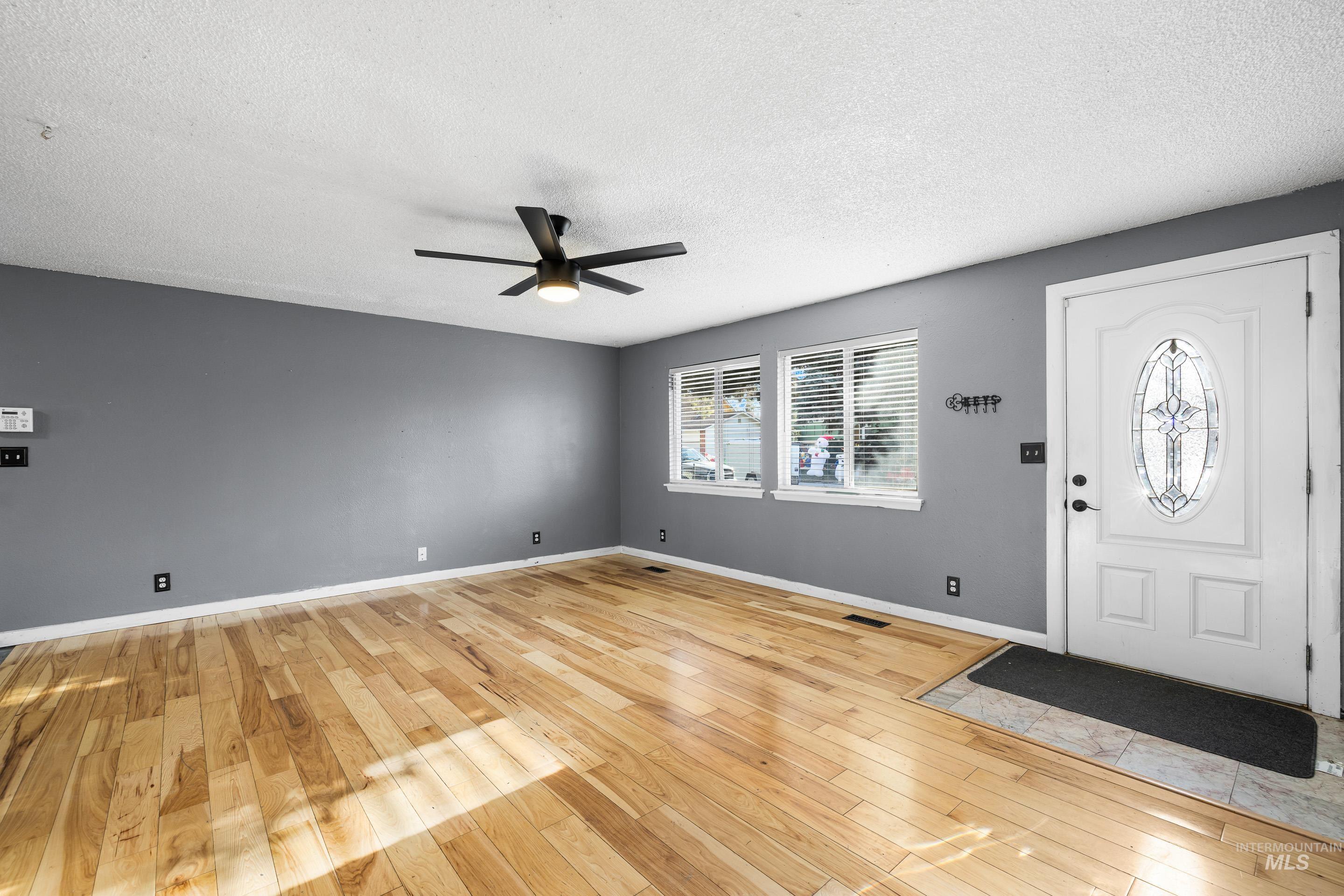 Entrance foyer featuring light wood finished floors, a textured ceiling, and a ceiling fan
