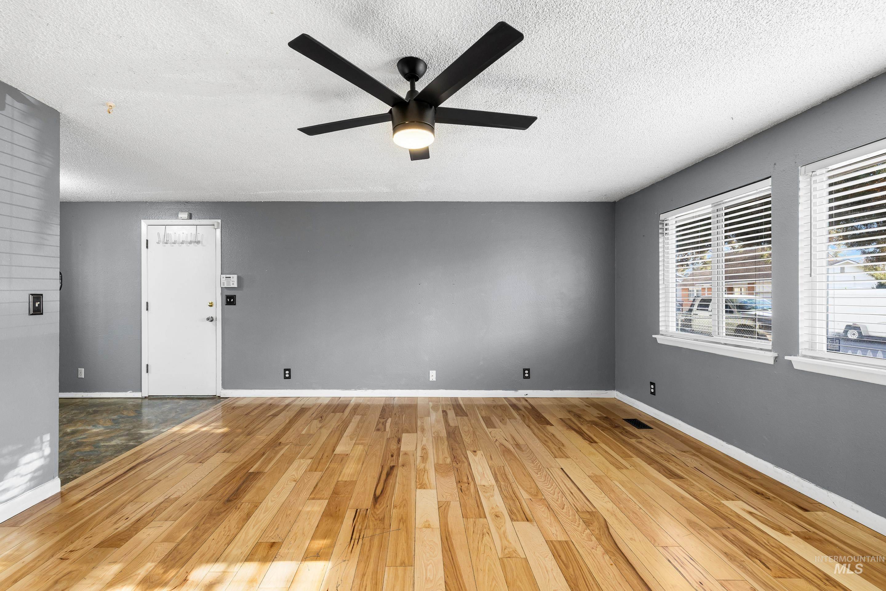 Unfurnished room featuring light wood-style flooring, a textured ceiling, and ceiling fan