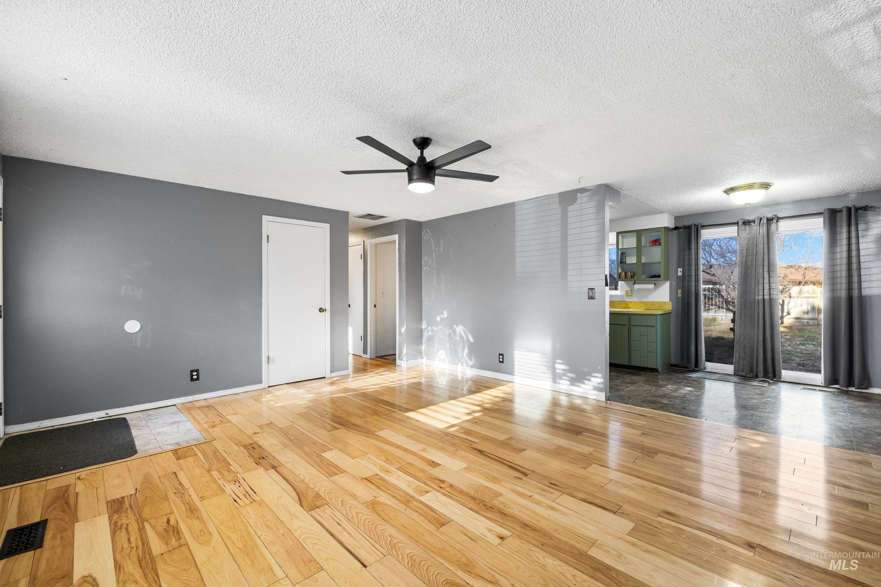 Unfurnished living room featuring a textured ceiling, light wood-style floors, and a ceiling fan