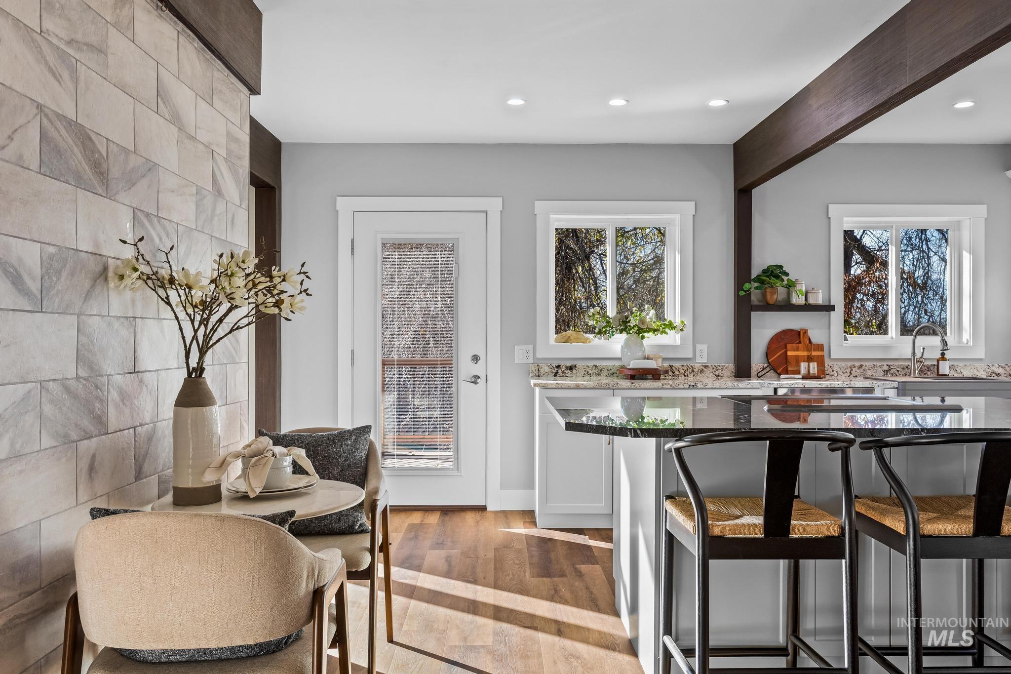 Kitchen featuring a kitchen bar, dark stone countertops, light wood-style flooring, recessed lighting, and white cabinets