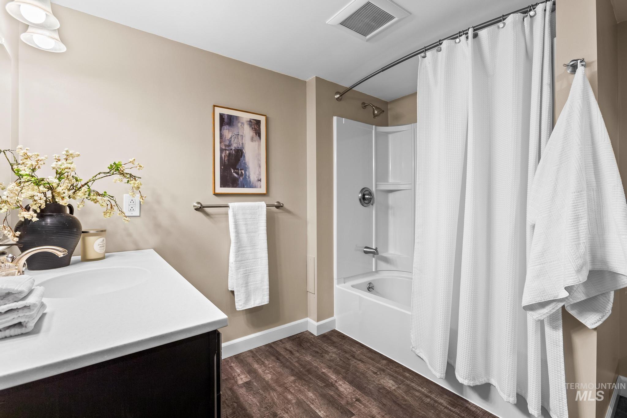 Bathroom featuring shower / bath combo, vanity, and dark wood-style flooring