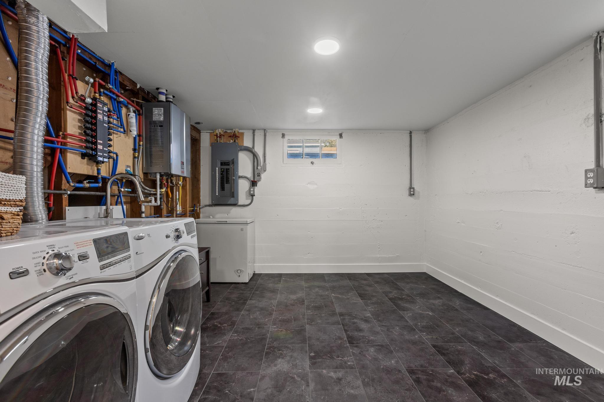 Laundry room featuring electric panel, washer and clothes dryer, and water heater