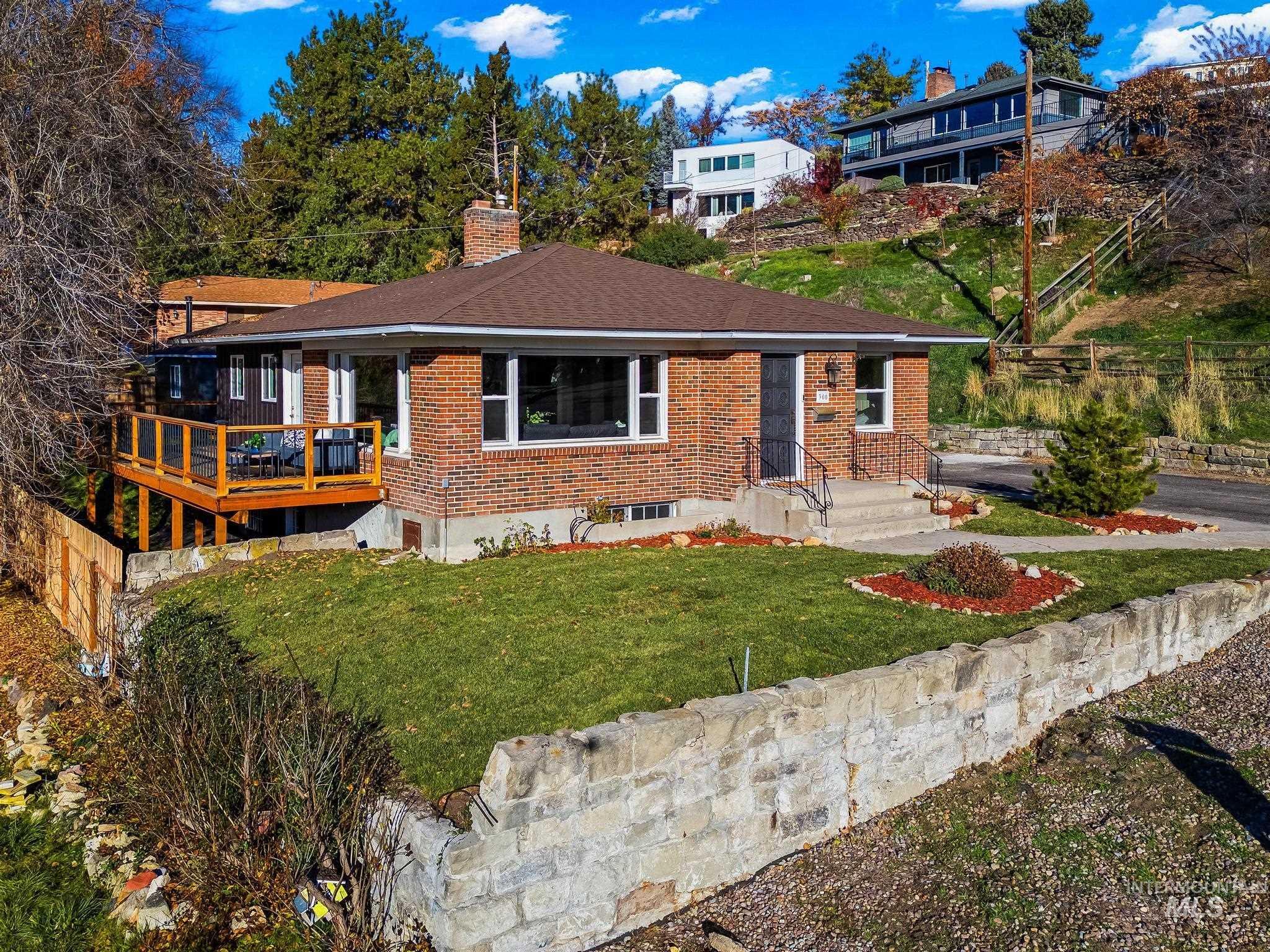 View of front of home with brick siding, a chimney, and a shingled roof