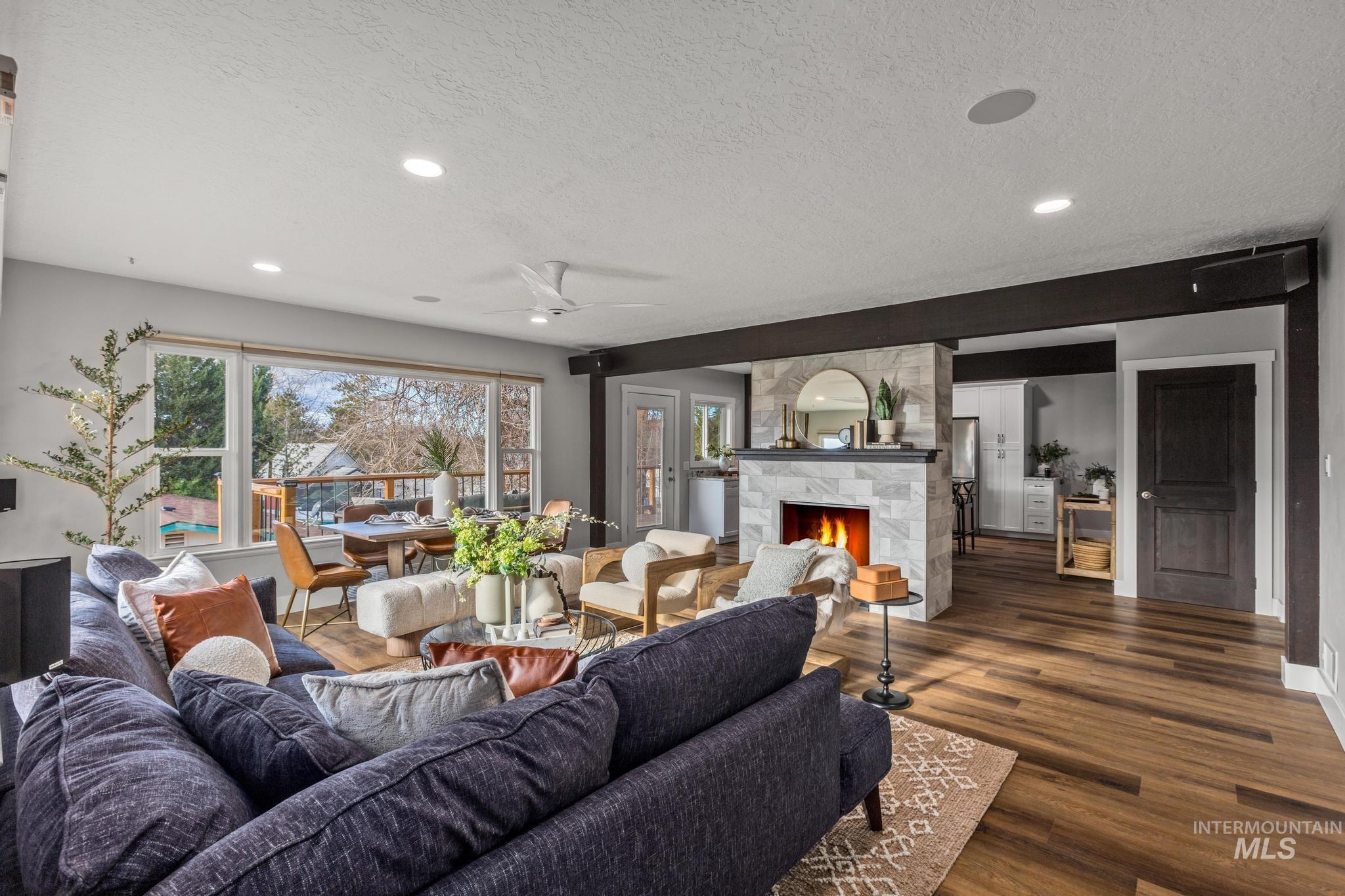 Living area featuring a textured ceiling, a ceiling fan, wood finished floors, a stone fireplace, and recessed lighting