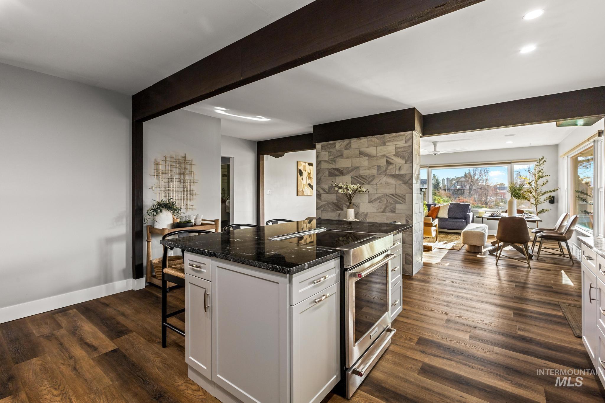 Kitchen featuring a breakfast bar, high end stainless steel range, dark stone counters, dark wood-style floors, and recessed lighting